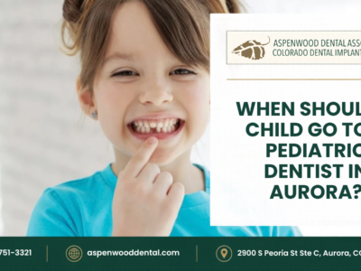 A smiling child points to their missing front teeth next to the text: “When should a child go to a pediatric dentist in Aurora?” along with Aspenwood Dental Associates contact information.
